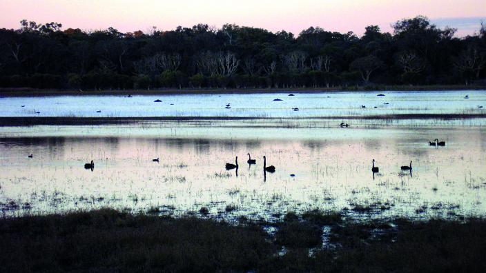 Colour photograph of lake with sunset reflecting on it
